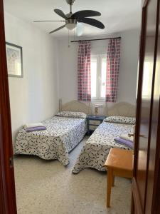 a bedroom with two beds and a ceiling fan at Home Chipiona Cadiz Parking in Chipiona +25 photos