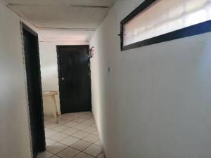 un corridoio con una porta nera e una parete bianca di Hospedaje Altamira a Barranquilla Altre 3 foto