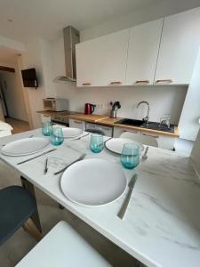 une cuisine avec des assiettes blanches et des verres sur un comptoir dans l'établissement Le cottages des remparts - le lodge, à Boulogne-sur-Mer