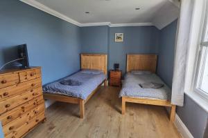 two twin beds in a room with blue walls at Trotternish Avenue Staffin IV51 9JU in Staffin