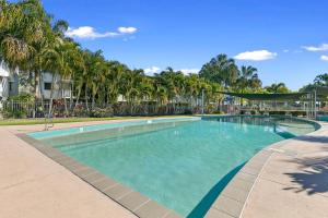 a large swimming pool with palm trees in the background at Ramada Encore by Wyndham Whale Cove in Hervey Bay