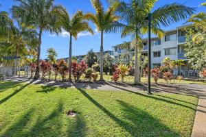 a park with palm trees in front of a building at Ramada Encore by Wyndham Whale Cove in Hervey Bay