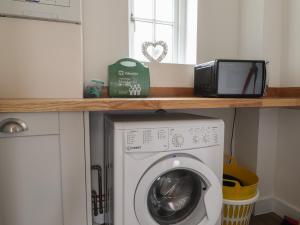 een wasruimte met een magnetron en een wasmachine bij Ty Caio in Newport