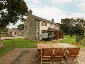 a wooden table and chairs in front of a house at Y Berth Ddu Farmhouse in Caernarfon