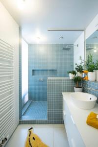baño con lavabo y ducha con azulejos azules en Island in Island, B&B boutique, Design et Vintage, en Namur