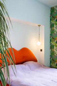 1 dormitorio con 1 cama con cabecero naranja y planta en Island in Island, B&B boutique, Design et Vintage, en Namur
