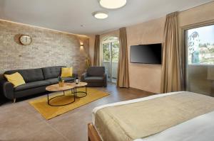 a bedroom with a bed and a couch and a tv at Romano Hotel Boutique in Safed