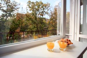 dos vasos de zumo de naranja sentados en una mesa junto a una ventana en APARTMENT on Sobornyi Avenue 61 en Oleksandriya