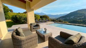 une terrasse avec mobilier en osier et une piscine dans l'établissement VILLA CORSA**** PISCINE VUE MER PANORAMIQUE, à Santa-Reparata-di-Balagna
