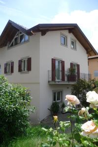 a white house with red shuttered windows and flowers at Agriturismo Casa Preti in Revò