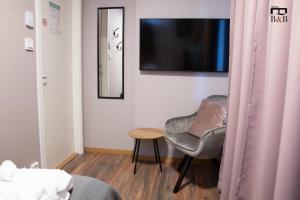 une chambre avec une chaise, une table et une télévision dans l'établissement Thunor B&B, à Skellefteå