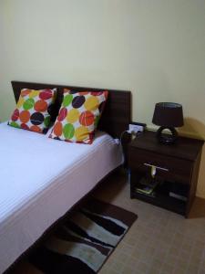 a bed with colorful pillows and a night stand with a table at Manuel's Apartment in Port Louis