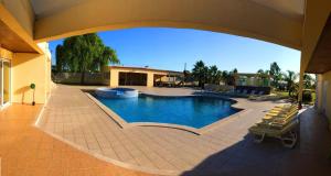 an outdoor swimming pool with chairs and a building at Villa Portugal in Palmela