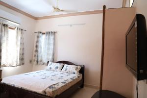 um quarto com uma cama e uma televisão de ecrã plano em DIVINEHOMESTAY COMFORT SUITE em Tirupati