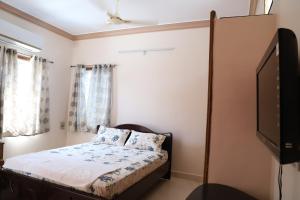 a bedroom with a bed and a flat screen tv at DIVINEHOMESTAY COMFORT SUITE in Tirupati