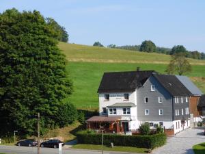 Pension Hofmann في Volkholz: منزل أبيض كبير أمام تلة خضراء