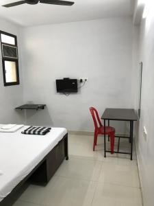 - une chambre avec un lit, une table et une chaise rouge dans l'établissement Prestige Guest House & Hostel, à Bilāspur