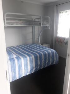 a bunk bed with a blue and white striped sheets at Comfortable 1 bedroom perfect for travelers or workers in Horotiu