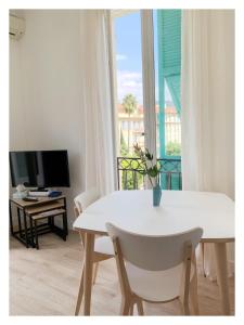 uma mesa branca e cadeiras num quarto com uma janela em Maison de Côte - Felice em Nice