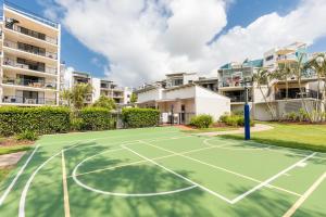 a tennis court in front of some apartment buildings at Marcoola Beach Resort in Marcoola