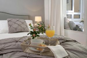uma cesta de comida e um copo de sumo de laranja numa cama em Living4Malaga Soho Orangerie Deluxe em Málaga
