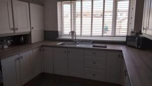 a kitchen with white cabinets and a sink at Luxury stay in the heart of Porthcawl in Porthcawl