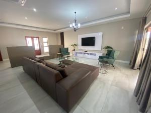 a living room with a brown couch and a tv at Khaya Elihle Guest House in Hazyview