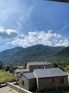 an old stone house with mountains in the background at Le Campcardos in Porta