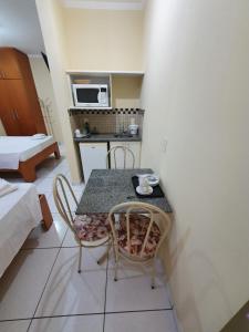 a small kitchen with a table and chairs in a room at JF Flat - Hotel in Ribeirão Preto