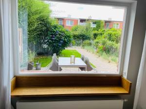 a window with a view of a table and a garden at Nordlys - Local & Style in Westerland (Sylt)
