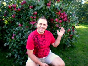 a man sitting in front of an apple tree at Nakvynė apgyvendinimo paslaugos DAIVOS NAKVYNĖS NAMAI in Biržai