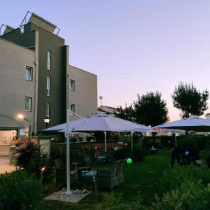 eine Terrasse mit blauen Sonnenschirmen, Stühlen und Tischen in der Unterkunft Hotel Calypso in Pontecagnano