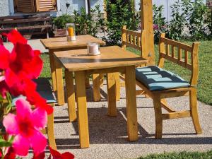 ein Holztisch und zwei Stühle neben einem Tisch und Blumen in der Unterkunft Auelehof in Leifers