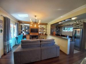 a living room with a couch and a kitchen at Casa Ari Candiago Gramado in Gramado