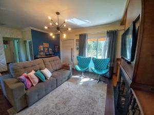 a living room with a couch and two chairs at Casa Ari Candiago Gramado in Gramado