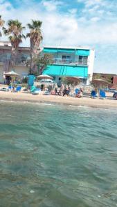 a beach with a blue building and people sitting on the beach at Maria Studio in Nea Karvali