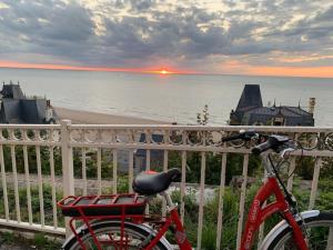 een rode fiets geparkeerd op een hek bij de oceaan bij L'Appartement vue mer de la Villa des Rosiers - Trouville sur Mer in Trouville-sur-Mer
