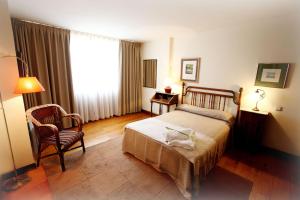 1 dormitorio con 1 cama, 1 silla y 1 ventana en Apartamentos Turísticos Las Nieves Playa, en Llanes