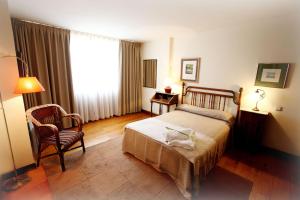 a bedroom with a bed and a chair and a window at Apartamentos Turísticos Las Nieves Playa in Llanes