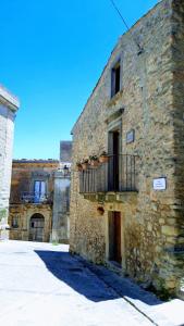 stary kamienny budynek z balkonem w obiekcie San Nicolò Holiday Home w mieście Montalbano Elicona