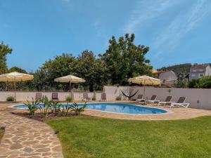 Una piscina con sillas y sombrillas en un patio. en Villa Galicia, en Caldas de Reis