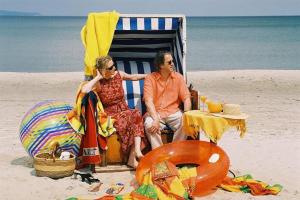 Ein Mann und eine Frau sitzen auf einem Stuhl am Strand in der Unterkunft Appartmentvermittlung Sommerwind in Binz