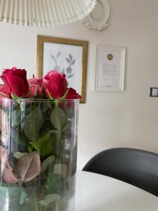 un vase rempli de roses rouges assis sur une table dans l'établissement Art Apartament, à Zielona Góra