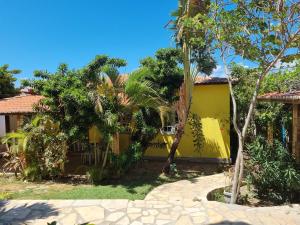 a yellow house with palm trees and a walkway at Casa do Galego no Residência Família in Canoa Quebrada