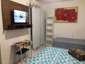 a small bedroom with a bed and a television at Pousada sol in Torres
