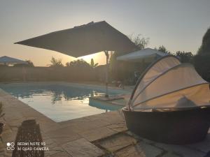 a swimming pool with an umbrella next to a swimming tub at B&B Country House Crema in Crema