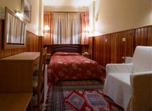 a small bedroom with a bed and a table at Hotel Bitouni in Metsovo