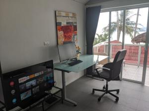 a room with a desk with a laptop and a television at Beach Apartment Samui (Bann Kanchana Bangrak) in Bophut