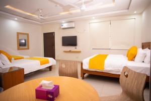 a hotel room with two beds and a table at Maati Spaces - Studio Apartments in Lahore