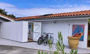 zwei Fahrräder, die außerhalb eines weißen Gebäudes geparkt sind in der Unterkunft les coquilles in Lanton